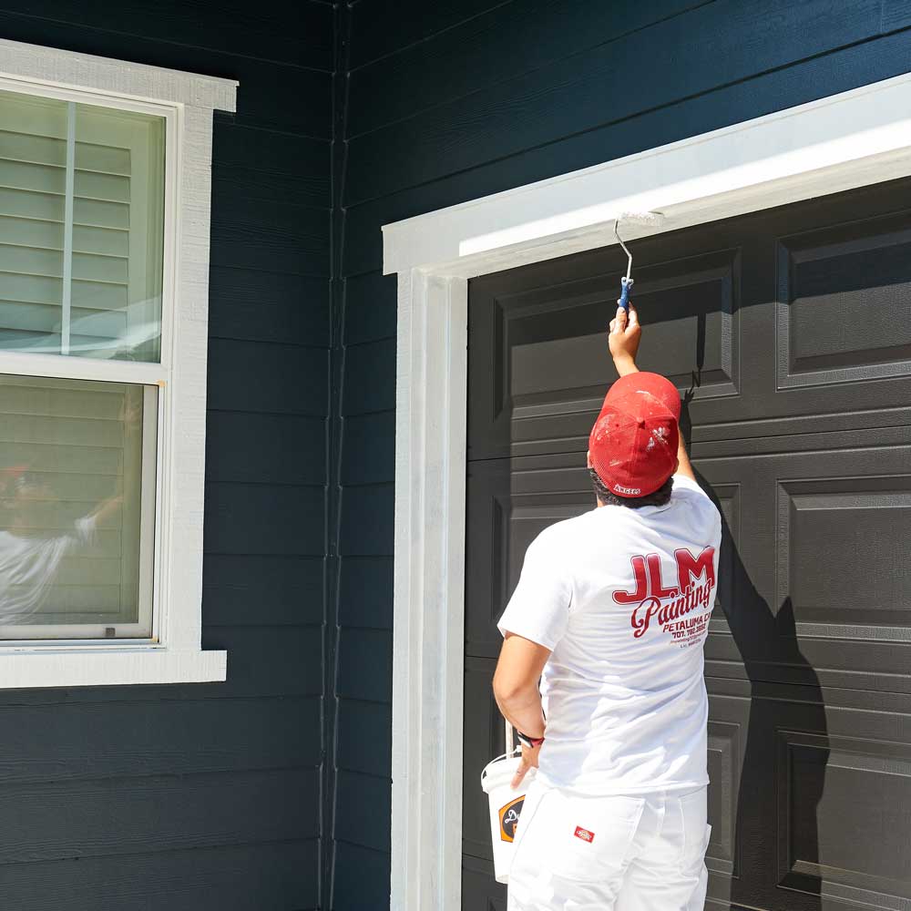 Professional painter painting around a garage door